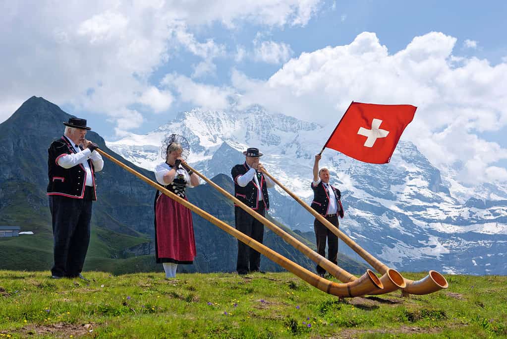 Alphorn player and flag waver in traditional swiss clothing
