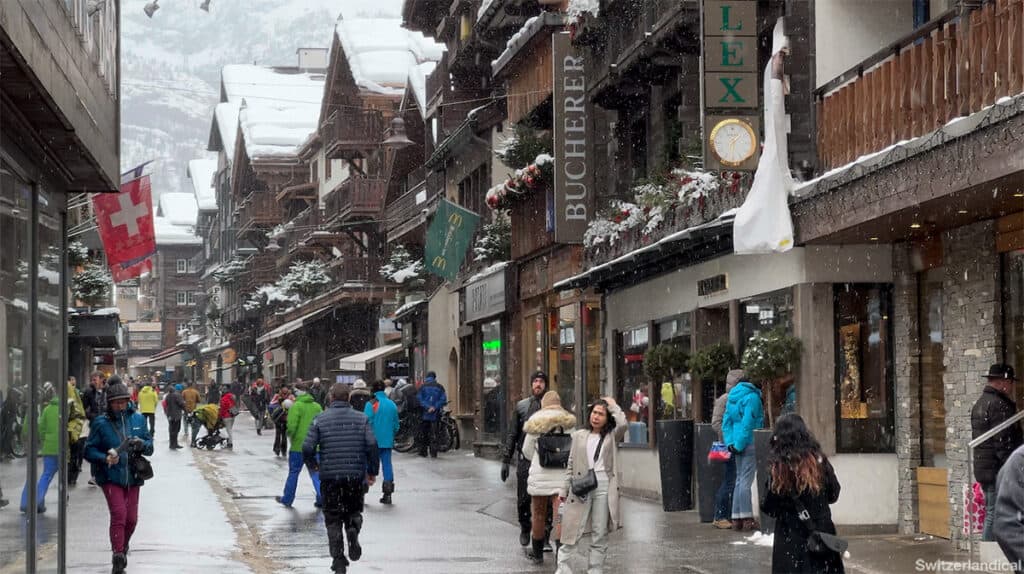 The main street in Zermatt, with wooden buildings and snow falling
